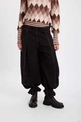 Jean de corte wide leg con efecto degradado en tonos marrón y negro. Presenta costuras verticales frontales y un diseño de puño ajustable en el bajo de la pierna.