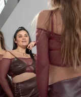 Conjunto de top y minifalda color borgoña. El top es strapless con mangas largas de tul y corpiño de cuero sintético. La minifalda es de cuero sintético con cordones laterales.