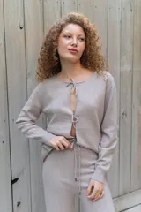 Conjunto bordó de punto, compuesto por un suéter con escote redondo y cierre frontal de lazos y un pantalón largo de corte recto.