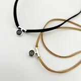 Gargantilla de cuero con dije circular de plata con piedra engarzada y cierre de plata.