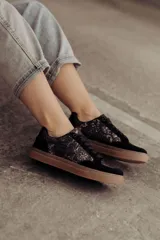 Zapatillas negras con paneles laterales de efecto piel de serpiente metalizado en tonos bronce y negro. Tienen cordones negros y suela de goma color caramelo.