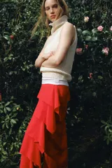 Falda midi de tiro medio en color rojo, confeccionada en tejido con viscosa. Presenta un diseño de capas horizontales con volantes laterales y cierre de cremallera oculta en la costura.