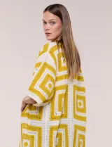 Cardigan largo confeccionado en tejido de punto calado estilo crochet, de color amarillo y blanco, con diseño geométrico de cuadrados, mangas amplias tipo kimono y corte abierto al frente.