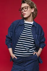 Camisa de manga larga con diseño de rayas verticales, corte oversize y hombros caídos. Presenta un juego de orientación de rayas en los bolsillos frontales y cierre con botones.