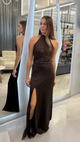 Vestido largo de fiesta color chocolate, con escote halter y cuerpo superior bordado con lentejuelas al tono. Presenta una falda fluida con tajo lateral profundo.