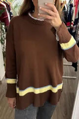 Sweater tejido de punto en color marrón, con cuello redondo y mangas largas. Presenta un diseño con franjas horizontales en tonos celeste y amarillo en los puños y en el ruedo inferior, con terminaciones acanaladas.