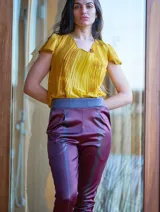 Pantalón de satén pintado a mano con diseño abstracto en tonos verde azulado y ocre.