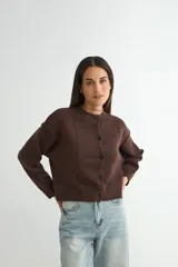 Cardigan de punto color marrón chocolate, con cuello redondo, cierre frontal de botones y diseño de costuras verticales visibles. Presenta puños y ruedo acanalados.