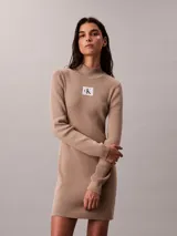 Vestido mini de Calvin Klein color beige, confeccionado en tejido de punto acanalado con cuello alto, manga larga y ajuste ceñido al cuerpo. Cuenta con una etiqueta con el logo de la marca en el pecho.