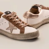 Zapatillas de cuero vacuno color blanco con aplique de estrella y talón superior color niquel italiano. Cartera en gamuza color taupe y suela de caucho.