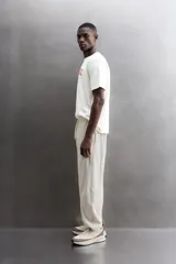Camiseta de algodón gris melange con cuello redondo, mangas cortas y efecto lavado. Presenta un estampado de texto frontal en color oscuro con efecto desgastado.