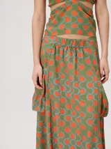 Falda midi de tiro alto y silueta evasé, confeccionada en algodón con diseño estampado geométrico en tonos verdes, naranjas y celestes. Cuenta con caída fluida, ruedo ligeramente acampanado y dos bolsillos cuadrados laterales.