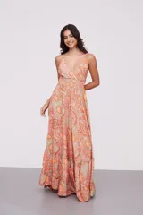 Vestido largo de tirantes finos con escote en V, diseño holgado y falda con volados en el ruedo. Presenta un estampado tipo paisley en tonos naranja y beige.