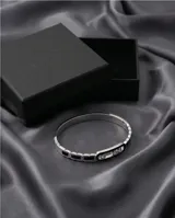 Pulsera esclava de acero con eslabones decorados con esmalte negro y un eslabón central alargado que contiene tres circonias móviles.