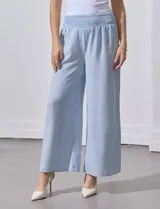 Pantalón largo de poliéster color beige con rayas verticales, pretina ancha elastizada en punto smock y pierna ancha.