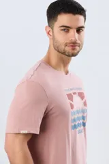 Remera blanca de manga corta y cuello redondo, con estampa frontal inspirada en el mar y atardeceres de verano con la inscripción 'Travel. Beach. Repeat.' y 'Legacy'.
