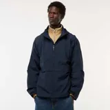 Chaqueta cortavientos azul marino con capucha, cierre frontal y bolsillos con solapa a la altura de la cintura. Presenta un diseño técnico y holgado.