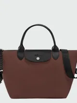Cartera de mano Longchamp modelo Le Pliage Energy tamaño S, confeccionada en lona de color bordó con detalles en cuero negro. Cuenta con doble asa superior, correa de hombro ajustable y extraíble, cierre principal con cremallera y solapa frontal con broche a presión.