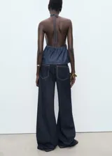 Pantalón de jean estilo wide leg, de tiro bajo y corte largo, con diseño de cinco bolsillos, trabillas para cinturón y cierre frontal con botón y cremallera.