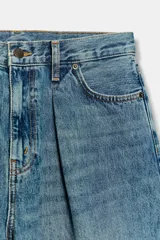 Bermuda de denim de tiro medio y corte wide leg, con diseño culotte, trabillas en la cintura y pliegues delanteros. Posee cinco bolsillos y cierre frontal con cremallera y botón.