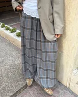 Pantalon de corte amplio con diseño a cuadros en tonos gris, blanco y naranja. Presenta cintura elástica con cordón ajustable y detalle de tiras en la botamanga para fruncir.