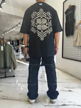 Remera oversize blanca con gran estampado en la espalda de diseño floral simétrico en tono oscuro. Cuenta con mangas cortas y calce holgado.