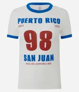 Remera de algodón con cuello redondo y mangas cortas, con vivos en color azul en cuello y mangas. Presenta una estampa frontal con la inscripción 'Puerto Rico 98 San Juan' en colores azul y bordó.