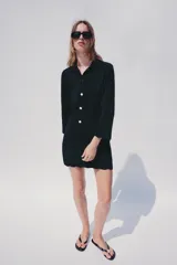 Chaqueta de punto color azul marino, con cuello solapa, manga larga y cierre frontal con botones metálicos. Presenta terminaciones en ondas en el bajo y los puños.