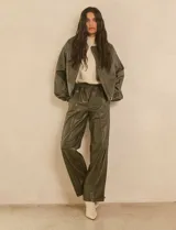 Chaqueta bomber de eco cuero color verde oliva, con cuello tipo solapa, cierre frontal metálico, bolsillos laterales y puños elásticos.