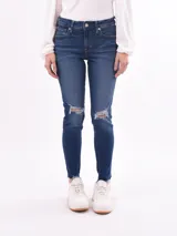 Pantalón de jean skinny azul con roturas en las rodillas y ruedo desflecado.