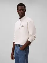 Buzo Calvin Klein de felpa de algodón color blanco off-white, con cuello alto, cierre de media cremallera y manga larga con puños acanalados. Cuenta con el logo de la marca bordado en el pecho.