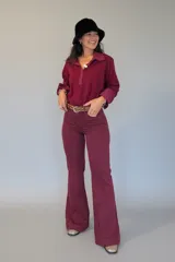 Pantalón de jean color borgoña de tiro alto, con corte recto y costuras verticales frontales que estilizan la silueta.