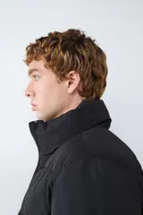 Campera acolchada de color negro con cuello alto, cierre frontal de cremallera y diseño de paneles horizontales. Cuenta con mangas largas y bolsillos laterales funcionales.