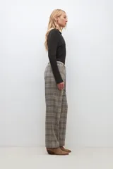 Pantalón largo de corte recto con estampado de cuadros escoceses en tonos beige, marrón y negro. Tiene cintura elástica con cordón ajustable.