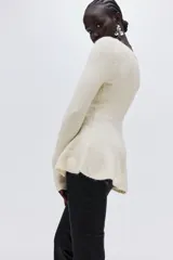 Buzo de punto acanalado color crema, con ajuste entallado, escote bote, mangas largas y detalle de peplum en la cintura.