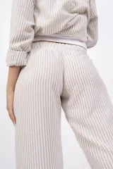 Pantalón largo de mujer, de corte amplio y tiro alto, con estampado a rayas verticales en tonos beige y blanco. Tiene cintura elástica con cordón ajustable.