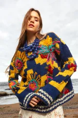 Sweater de lana tejido y bordado a mano con calce holgado, cuello a la base y puños. Diseño con rayas horizontales en azul y amarillo, y bordados de flores multicolores. Talle único, similar a un M/L.
