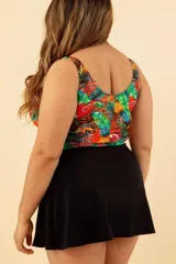 Vestido de baño enterizo con estampado de hojas, piñas y animal print. Tiene escote con abertura en forma de gota y moño negro. La parte inferior es una falda negra.