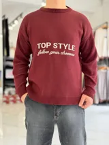 Sweater bordó de tejido de punto con cuello redondo, manga larga y el texto "TOP STYLE follow your dreams" en el pecho.