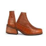 Botín de cuero blanco con textura de crocco y charol, diseño con calados circulares y aberturas laterales en forma de V. Cuenta con taco foliado de madera y vira cosida.