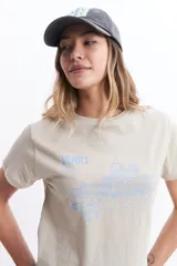 Remera de algodón color beige claro, de manga corta y cuello redondo, con un estampado lineal azul claro que representa la silueta de Venecia.