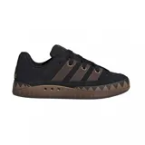 Championes adidas modelo Adimatic, de diseño robusto inspirado en el skate de los años 90. Presenta un exterior de gamuza negra con las icónicas tres tiras laterales en color marrón, cordones gruesos y una suela de goma dentada con patrón en zigzag.