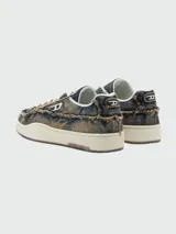 Zapatillas Diesel modelo S-Tracker-D Low, confeccionadas en denim con efecto desgastado y bordes desflecados. Presentan cordones blancos, suela de goma color crema y el logo de la marca en el lateral y la lengüeta.