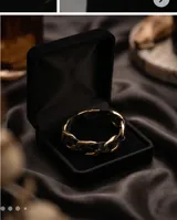 Pulsera de diseño trenzado que combina tiras de cuero negro con eslabones de acero en tono dorado. Cuenta con un cierre magnético integrado.
