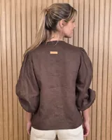 Camisa color beige de lino con mangas abullonadas tres cuartos y cierre frontal mediante múltiples lazos para atar.
