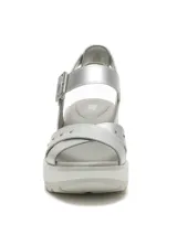 Sandalia de plataforma color plateado con acabado texturizado, diseño de tiras cruzadas en el empeine con detalle de tachas metálicas y cierre de hebilla ajustable en el tobillo. Cuenta con una suela dentada de goma en tono gris claro.