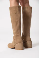 Bota bucanera de caña alta color visón, confeccionada en cuero descarne, con cierre lateral y taco cuadrado forrado.