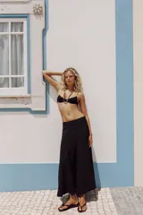 Falda larga de tiro alto, color negro, con diseño fluido y cintura elástica. Cierre lateral con cremallera oculta en costura.