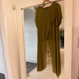 Blusa verde pistacho de gasa, de corte holgado, mangas cortas con vuelo y diseño asimétrico con superposición frontal.
