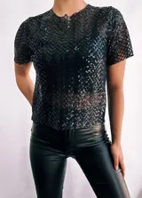 Remera negra de mangas cortas confeccionada en tejido de red con lentejuelas. Incluye top negro de breteles finos para usar debajo.